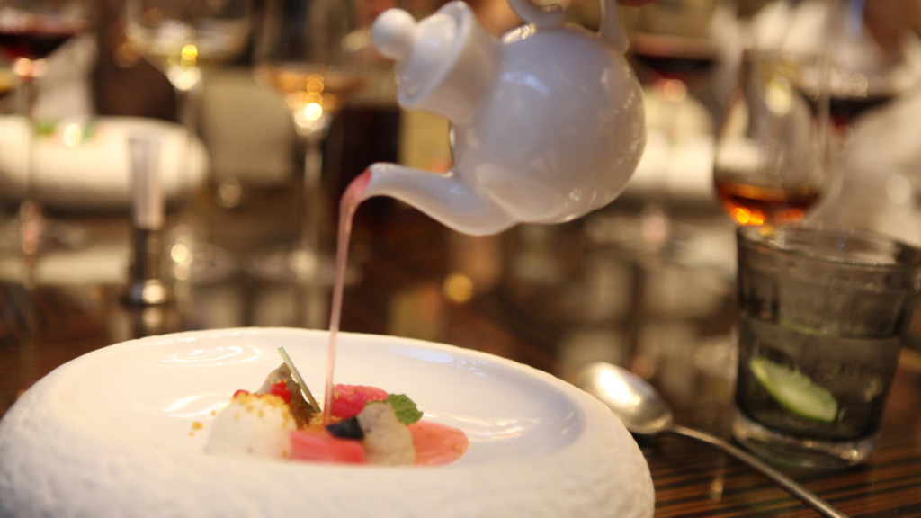 Server pours a pink liquid from a teapot onto a high-end dessert. A staple at most Michelin-starred restaurants.