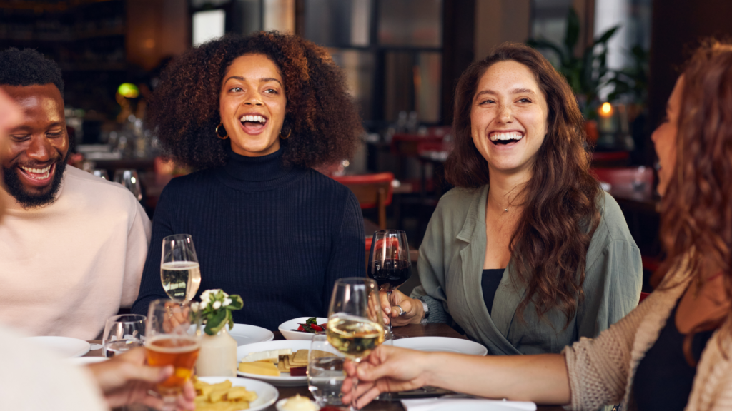 a group of people laughing while enjoying wine and a meal at a  Micheline starred restaurant.  SOmething that a group can do while on vacation in Lisbon.