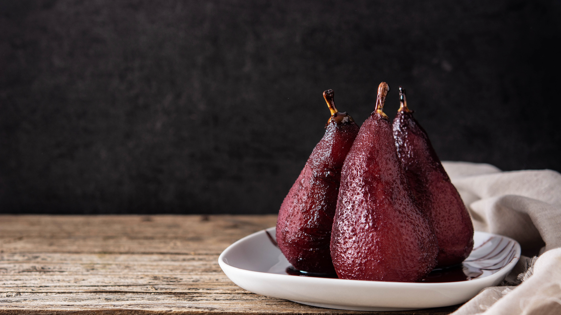 Two deep red pears gently poached in rich red wine, elegantly presented as a traditional Portuguese dessert you can enjoy in Portugal