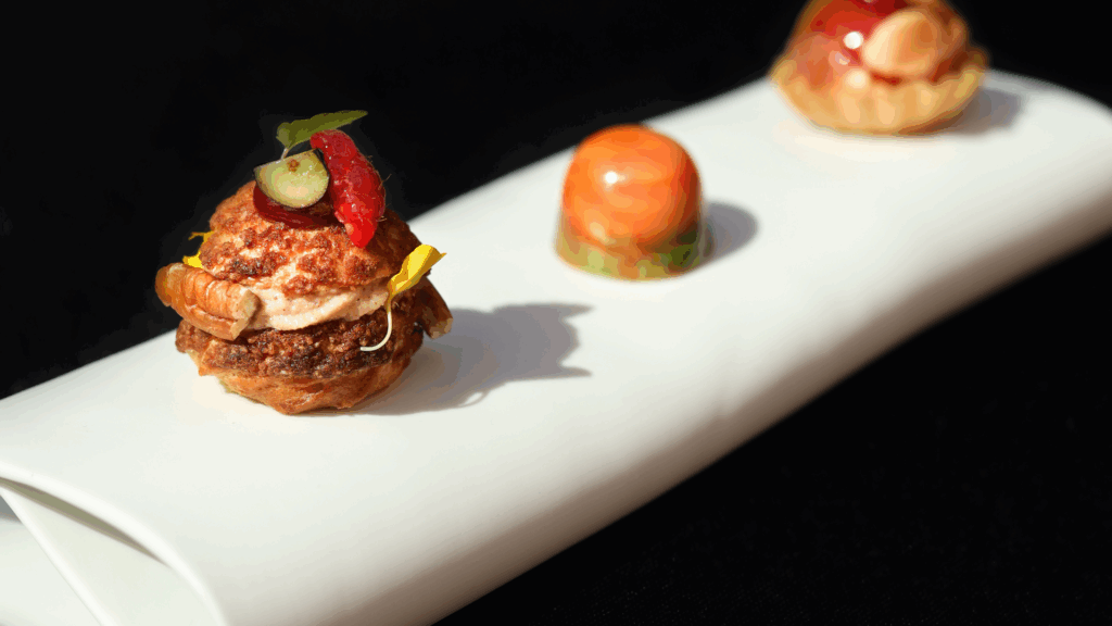 Three colorful bite-sized desserts on unique rectangular China plate – vibrant foodie travel desserts at Michelin-starred restaurant